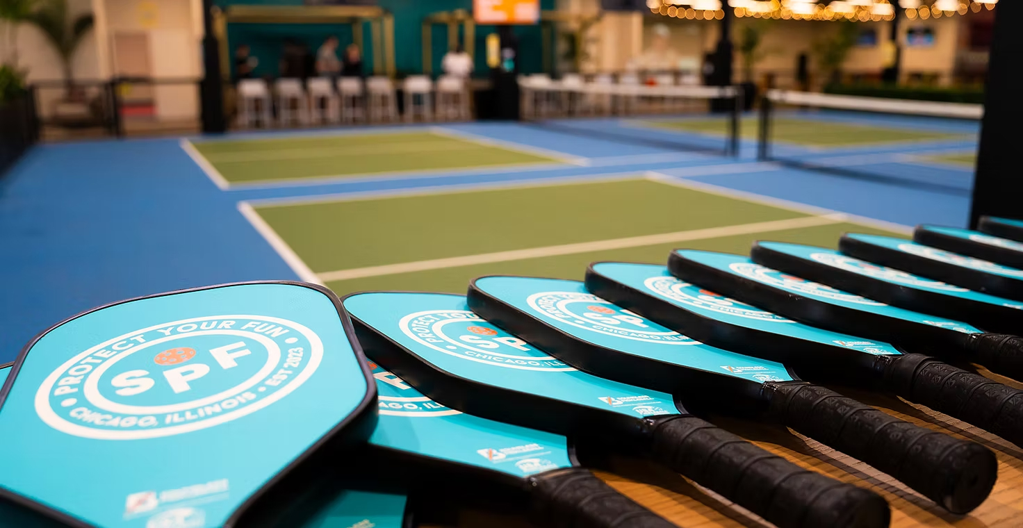 Rows of SPF-branded pickleball paddles lined up beside the courts at SPF Lincoln Park